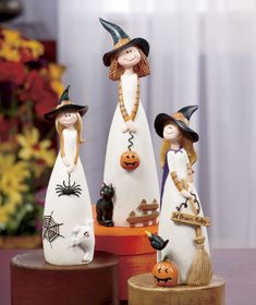 three ceramic figurines with witches and pumpkins on top of a wooden stand