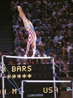 a man on the balance beam in front of an audience at a sporting event,