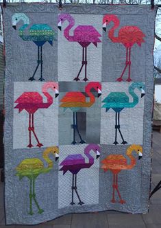 a quilted wall hanging with colorful flamingos on it's sides and the words,