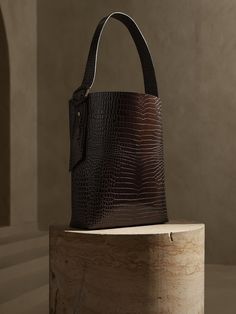 Crafted in Italy with embossed crocodile-effect leather, this luxurious bucket bag is ideal for everyday adventure with impeccable craftsmanship and effortlessly sophisticated style.  Strap with buckle closure.  Interior pocket with zip closure.  Two Dress Shoes Flats, Trendy Hats, Crocodile Handbags, Trendy Hat, Bag Display, Signature Hardware, Leather Bucket Bag, Leather Bucket, Dark Gold