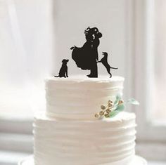 a wedding cake topper with a silhouette of a couple and two dogs on it