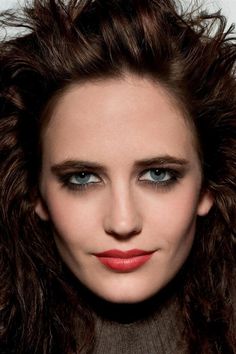 a woman with long brown hair and blue eyes is posing for the camera while wearing red lipstick