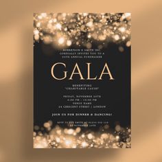 a black and gold galaa party card with sparkles on the edges, in front of a brown background