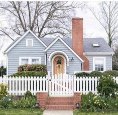 a blue house with white picket fence and flowers