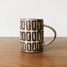 a brown and white coffee cup sitting on top of a wooden table next to a wall