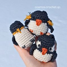 three small crocheted penguins sitting on top of someone's hand in the snow