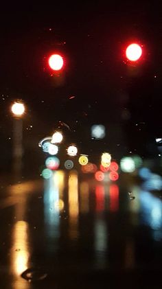 blurry image of street lights at night with rain on the ground and wet pavement