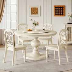 a white dining table with four chairs around it in a room that is painted white