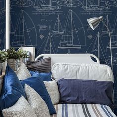 a blue and white bedroom with sailboats drawn on the wall next to the bed