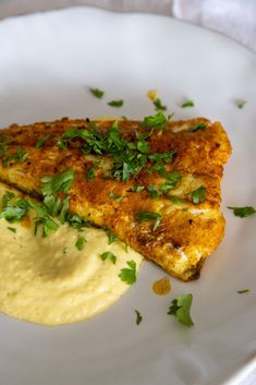 two pieces of fish on a plate with sauce and parsley sprinkled on top