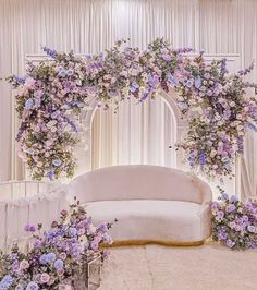 a white couch sitting in front of a flower covered wall with purple flowers on it