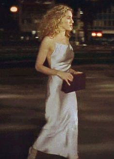 a woman in a white dress is walking down the street