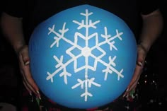 a person holding a large blue ball with white snowflakes on it's side