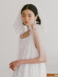 a woman in a white wedding dress with a veil on her head and hands behind her back