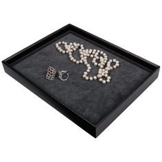 a black tray with pearls and rings on it that says joy in the middle, surrounded by other jewelry items