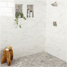 a white bathroom with marble tile and wood stumps on the floor next to it