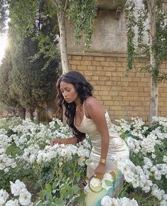 a woman in a white dress picking flowers