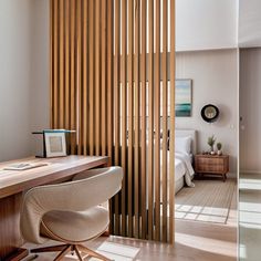 a room with a desk, chair and wooden slatted partition in the wall