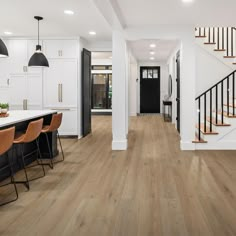 an open floor plan with white walls and wood floors, black railings, and wooden bar stools