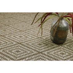 a vase with some plants in it sitting on a tablecloth that is made out of woven material