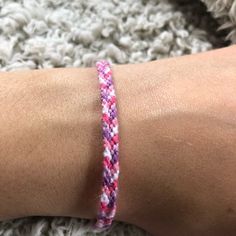 a person's arm with a pink and purple bracelet on top of white carpet