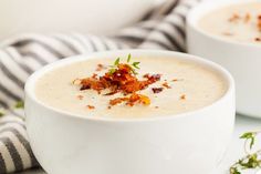 two white bowls filled with soup and garnished with bacon