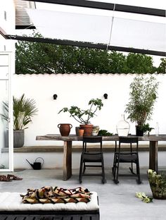 an outdoor dining area with potted plants on the table