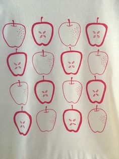 a white t - shirt with red apples drawn on it