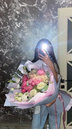 a woman holding a bouquet of flowers in front of a door with the light shining on her face