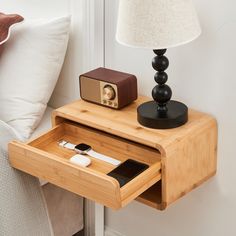 a bedside table with an electronic device in it and a lamp on the nightstand next to it