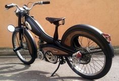 an old style motorcycle parked in front of a tan building with no one on it