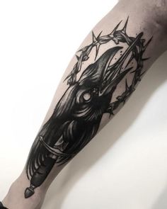 a man's arm with a black and white tattoo design on it, holding a knife