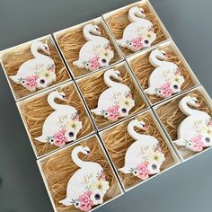 twelve swan shaped coasters with flowers in a box