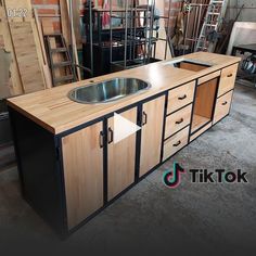 a kitchen island made out of wood and metal with a stainless steel sink in the center