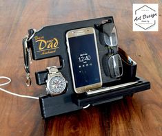 a cell phone, watch and other items are sitting on a table with the tag just dad attached to it