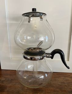 a glass coffee pot with a black handle