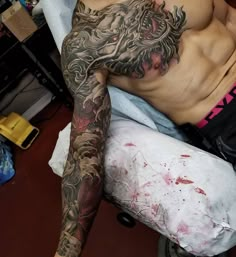 a tattooed man laying on top of a bed