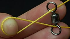 a person holding a yellow string with a small metal object on it's end