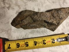 a piece of rock next to a measuring tape on top of a white cloth covered floor