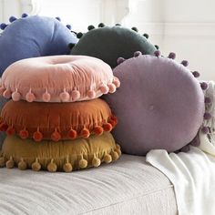 four pillows stacked on top of each other with pom poms around the edges