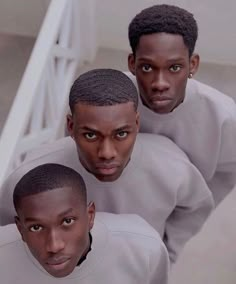 three black men in grey sweatshirts standing next to each other on the stairs looking at the camera