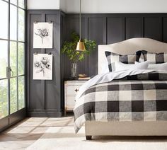 a black and white bedroom with wood paneled walls, plaid bedding and pillows