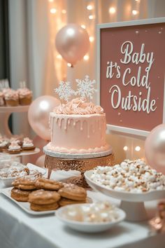 baby it's cold outside dessert table with pink frosted cake, cookies and marshmallows