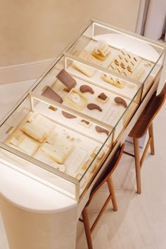 a glass display case with several pieces of art on it and two chairs next to it