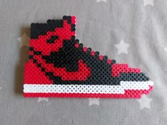 a pair of red and black sneakers made out of perler beads on a bed