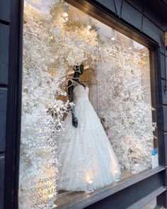 a wedding dress displayed in a window with snowflakes on the outside and behind it