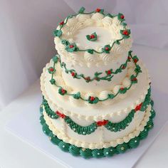 a three tiered cake with holly decorations on it's sides and white frosting