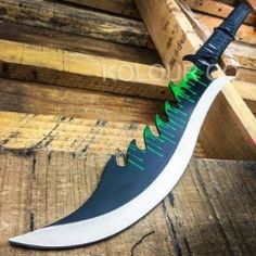 a knife that is on top of some wooden planks with green and white accents