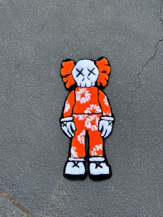 an orange and white teddy bear with flowers on it's body sitting on the ground