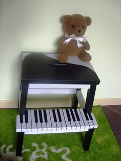 a teddy bear is sitting on top of a piano in a room with green carpet